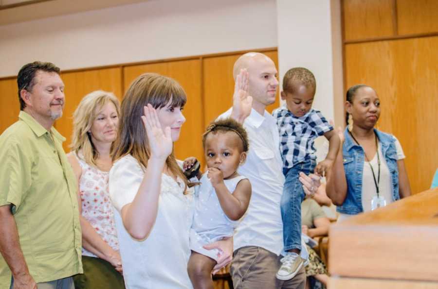 Couple take an oath in front of a judge while officially adopting their children