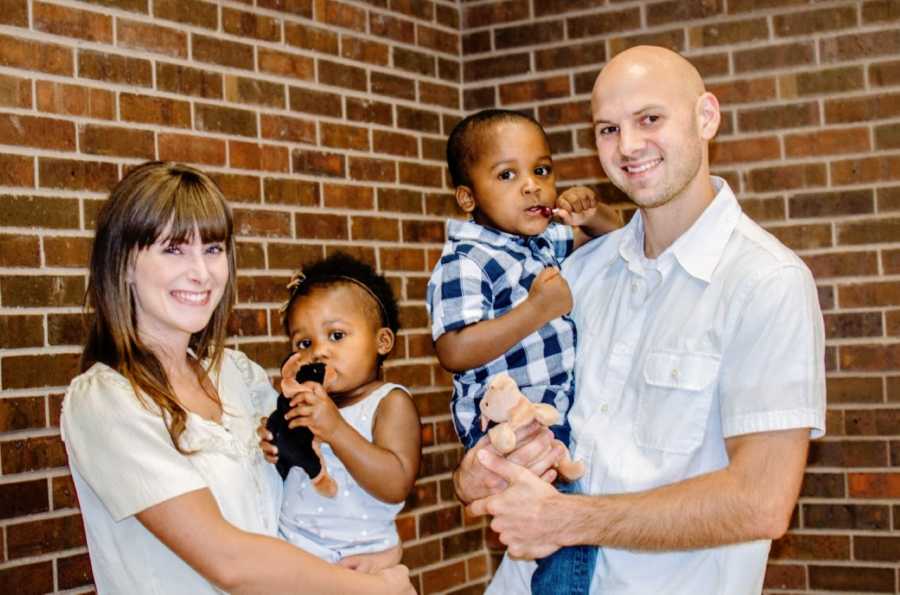 Parents smile and hold their newly adopted children outside of the courthouse