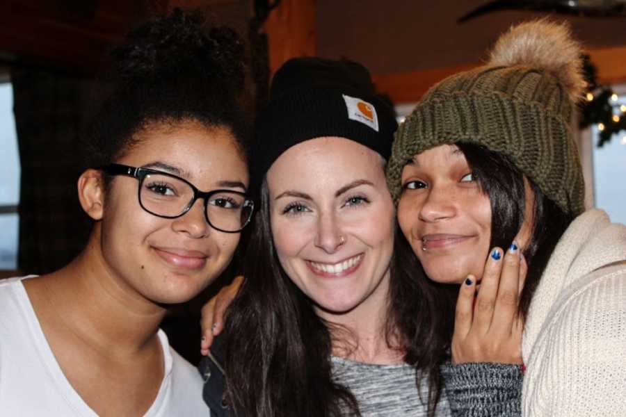 Woman smiles and hugs her two adopted sisters