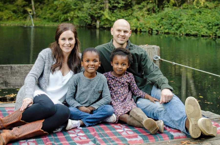 Couple with their adopted children pose for a family photo next to a lake