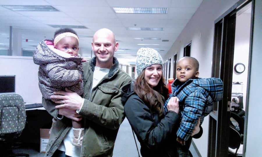 Adoptive parents hold their adopted siblings in winter gear