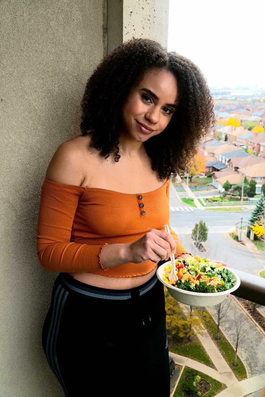 woman in orange shirt holding a bowl of food