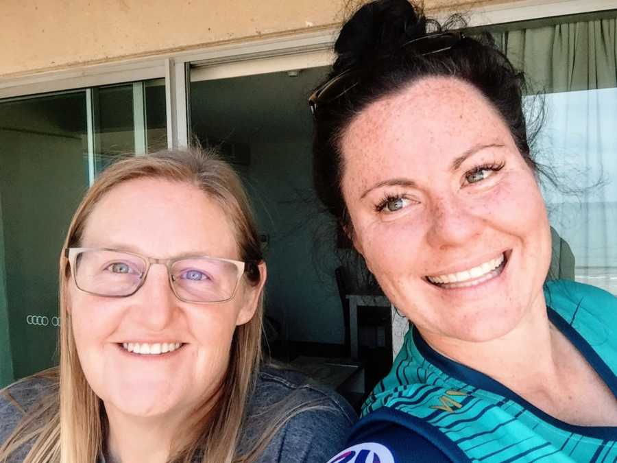 Lesbian couple take a selfie together while enjoying some time out in the sun on a balcony