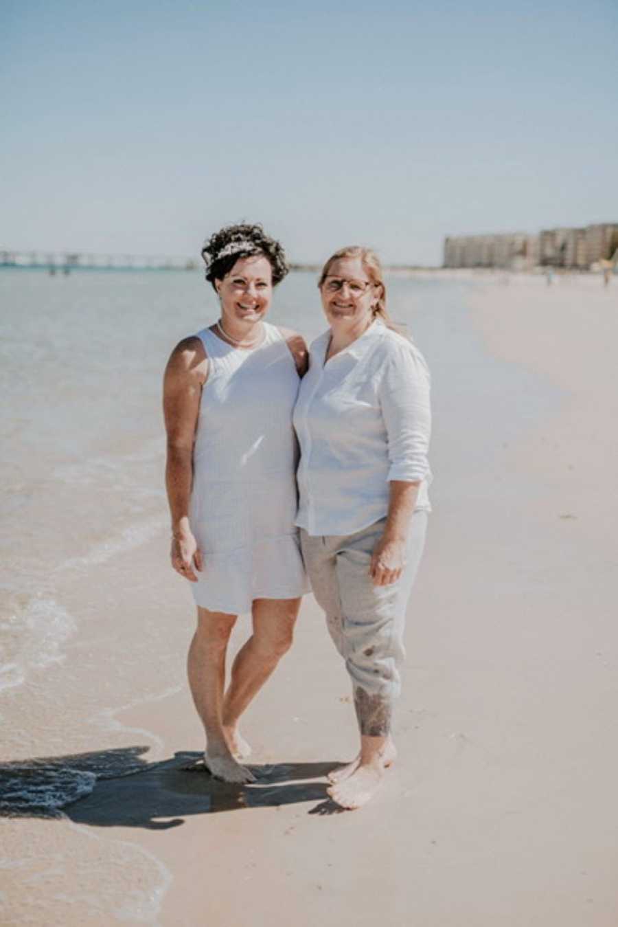Lesbian couple get married on the beach, surrounded by their closest friends and family