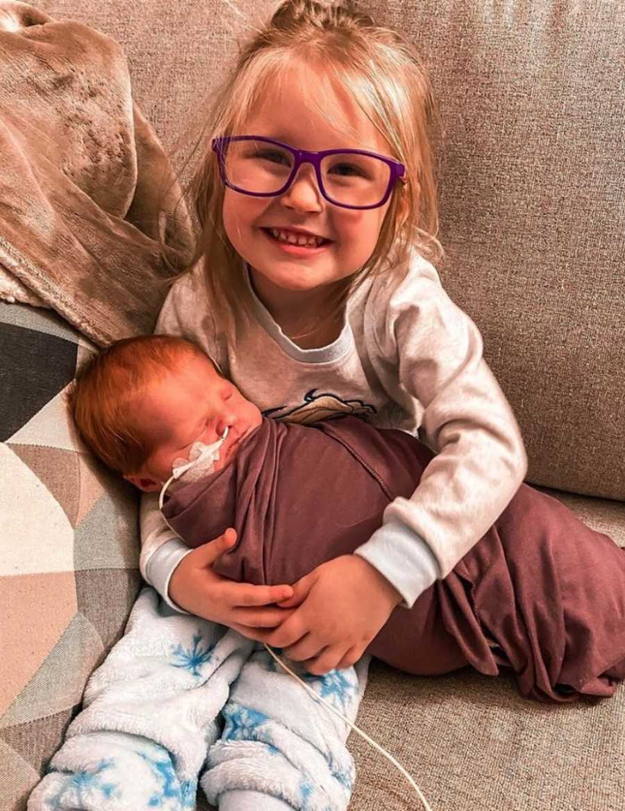 Big sister holding newborn sister