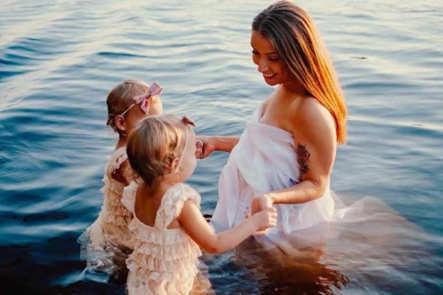 mom with two young twin daughters in lake