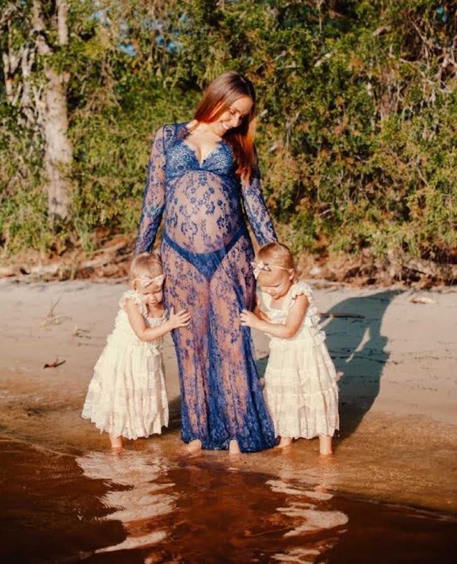 woman in lake with young twin daughters