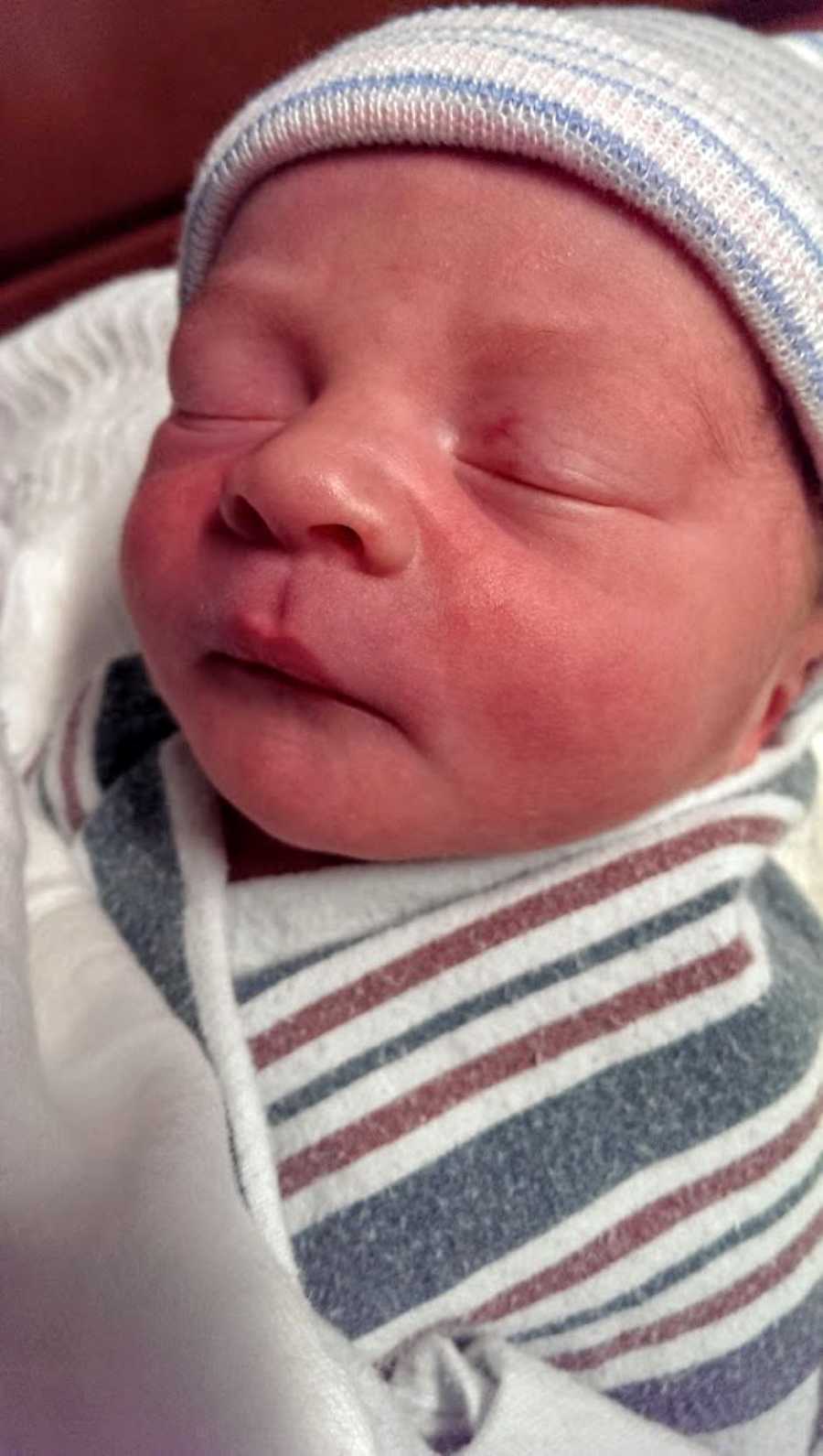 Newborn baby boy swaddled in hospital blankets with a beanie on his head