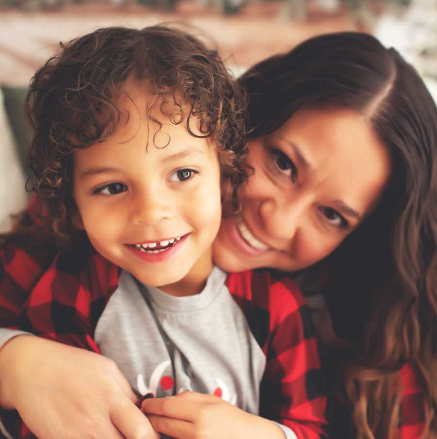 Woman hugs her adoptive son for a family photo while they both smile