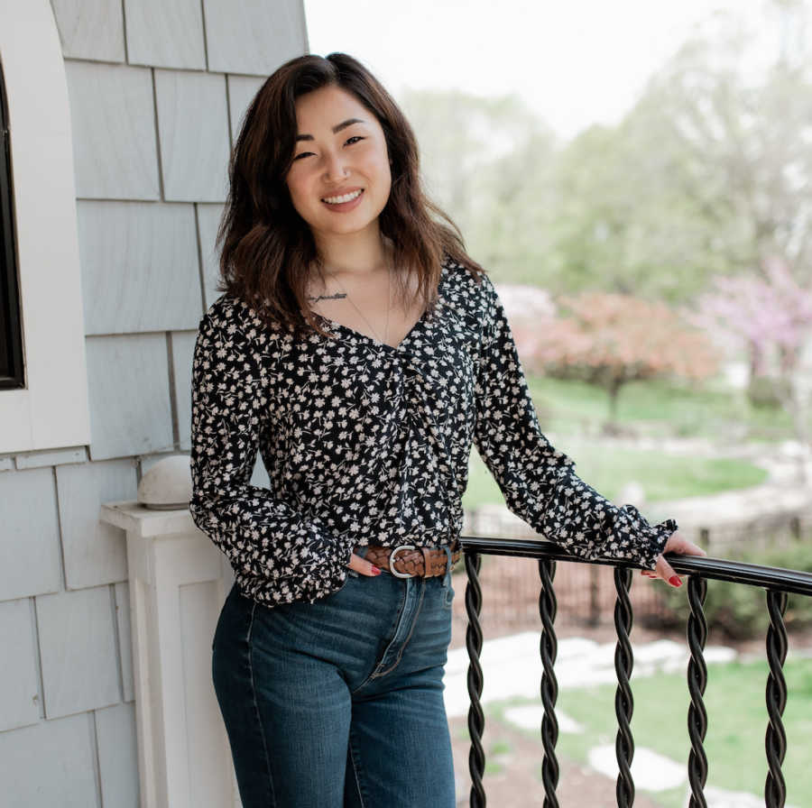 woman holding railing outside, smiling