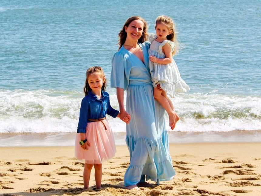 妈妈和两个女儿在海滩上与女儿们合影留念