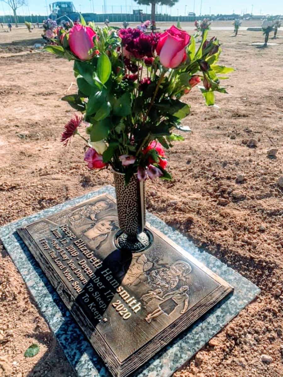 Photo of a child's grave with pink flowers on it