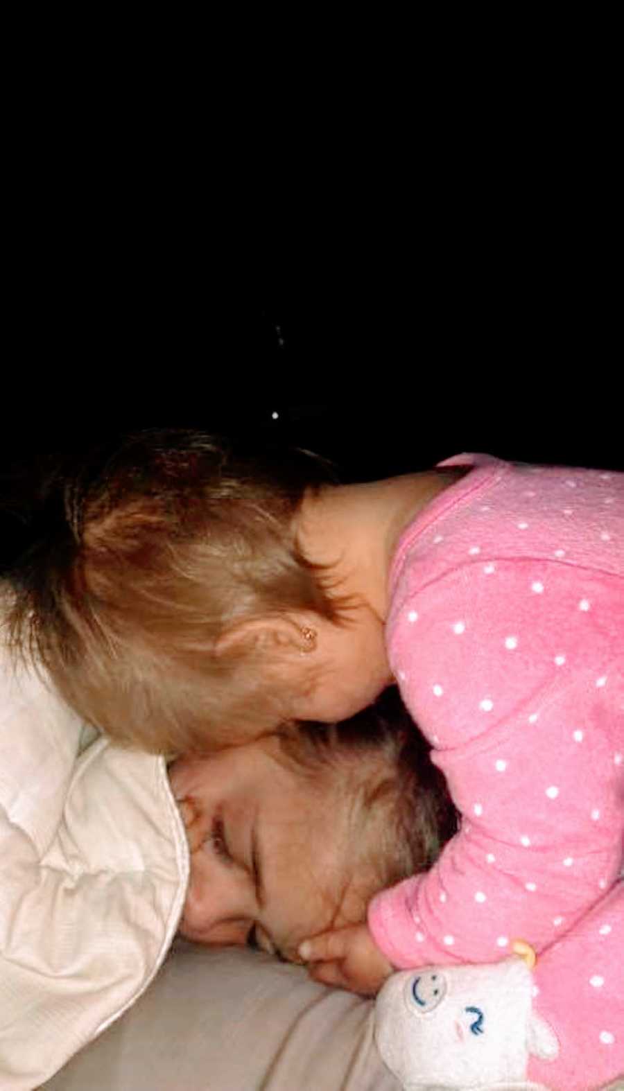 Two sisters cuddle in the dark at bedtime