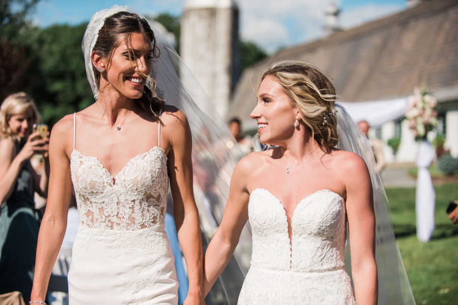 wedding photo of two brides holding hands and looking at each other