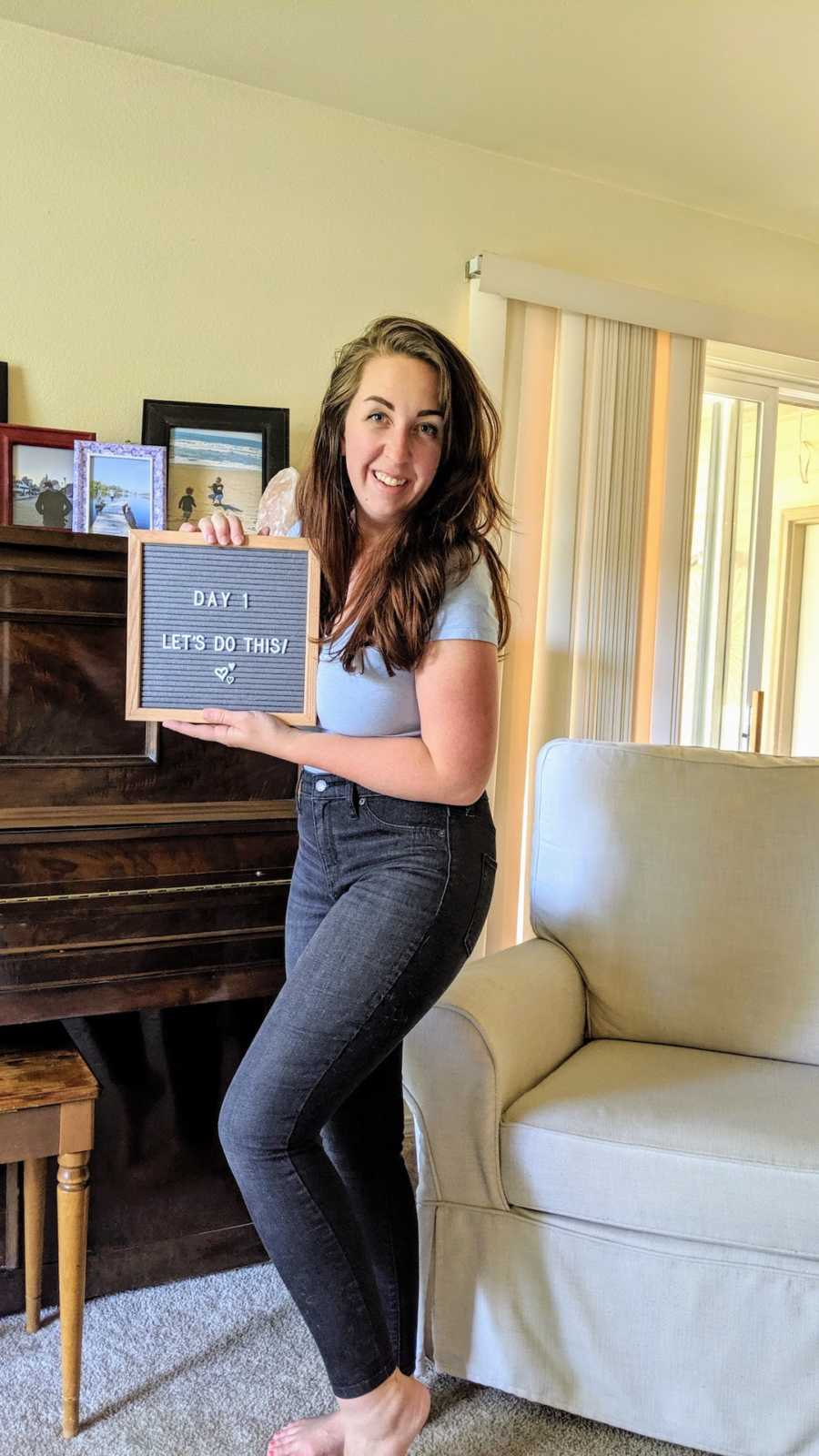 Woman holding letter board in living room and smiling