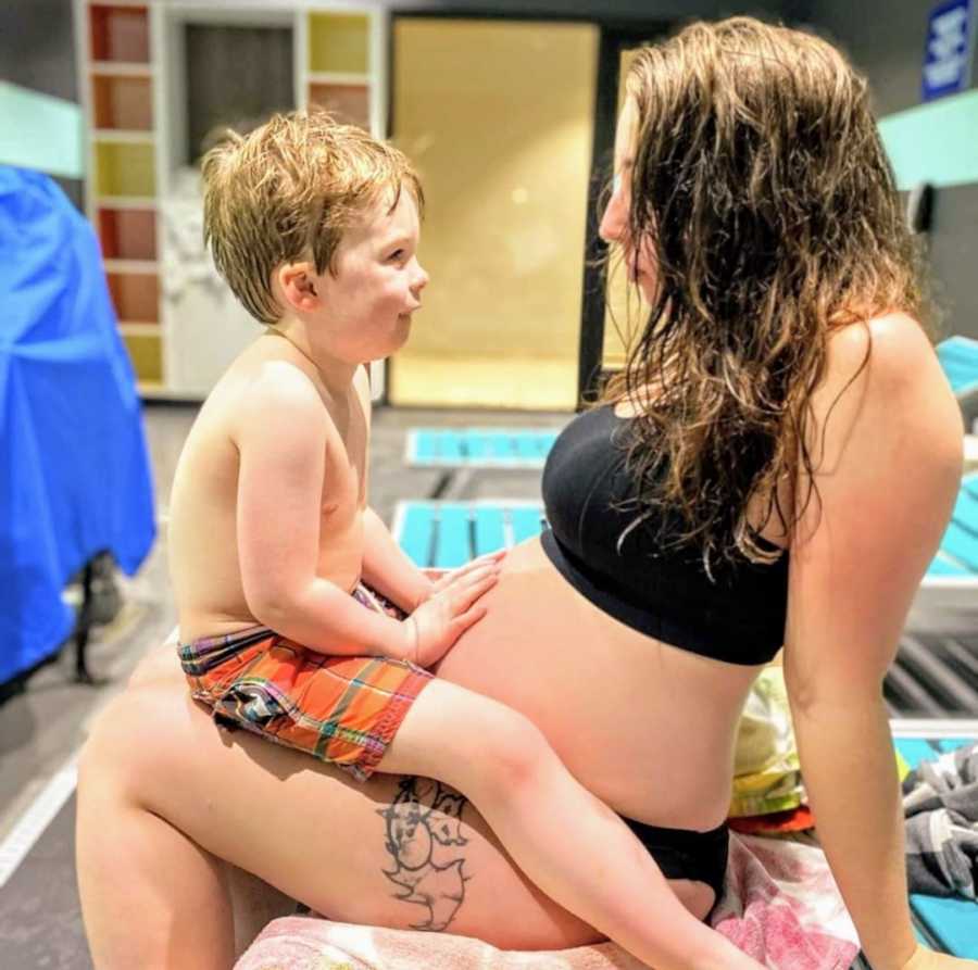 Son sitting on pregnant mother's lap as they look at each other