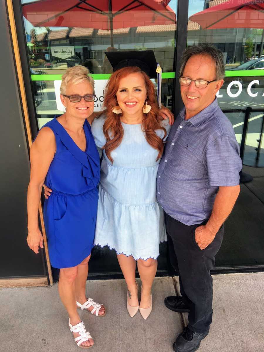 Woman standing with mother and father wearing graduation cap