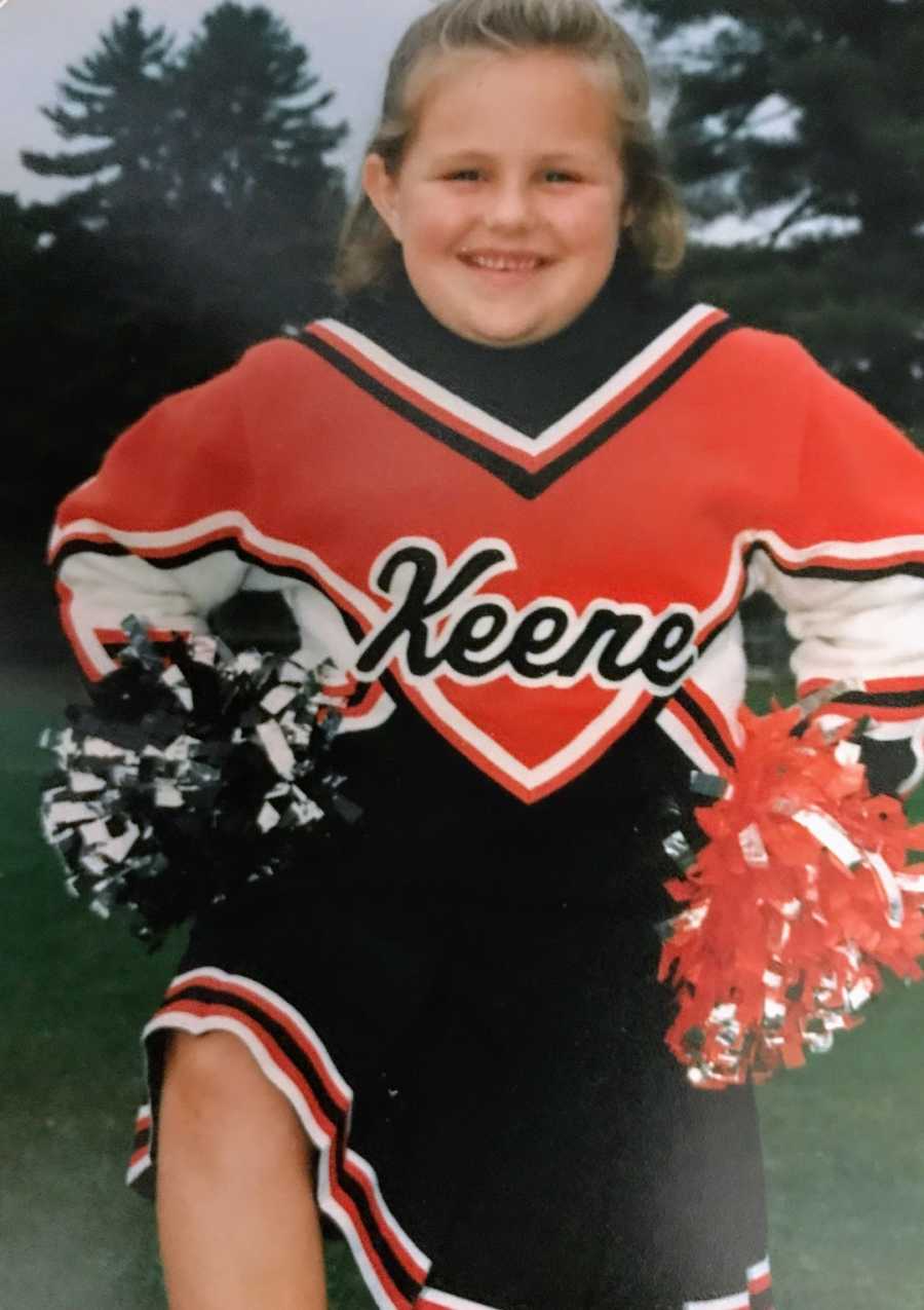 Young girl wearing cheerleading uniform smiling