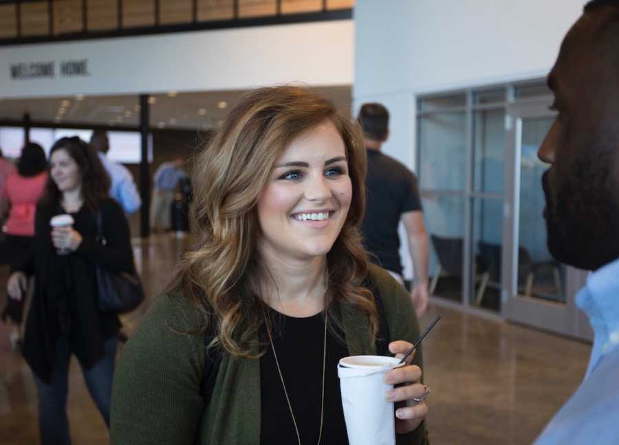 Woman at conference holding coffee cup and talking to man