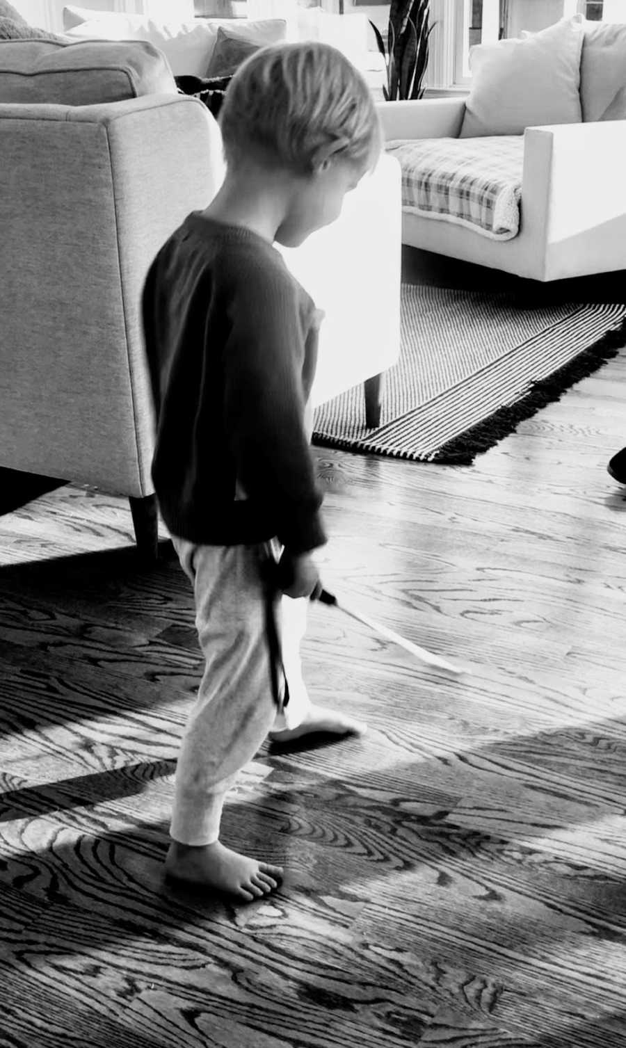 Black and white photo of young boy using walking stick