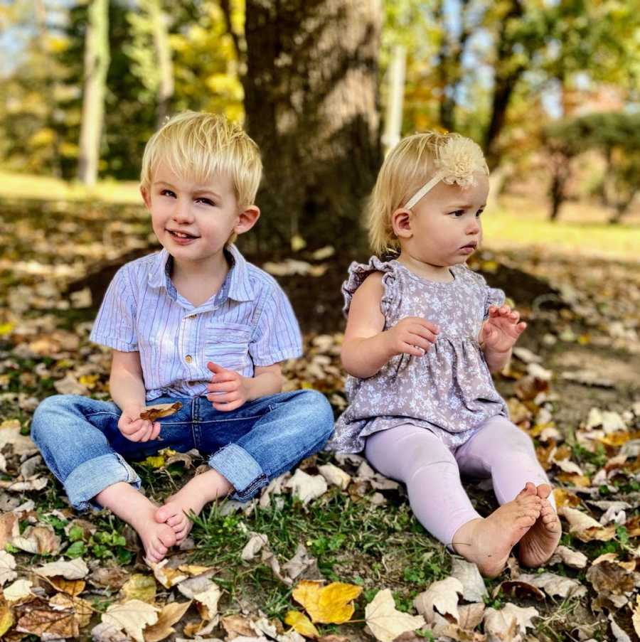 Brother and sister sitting outside on fall day