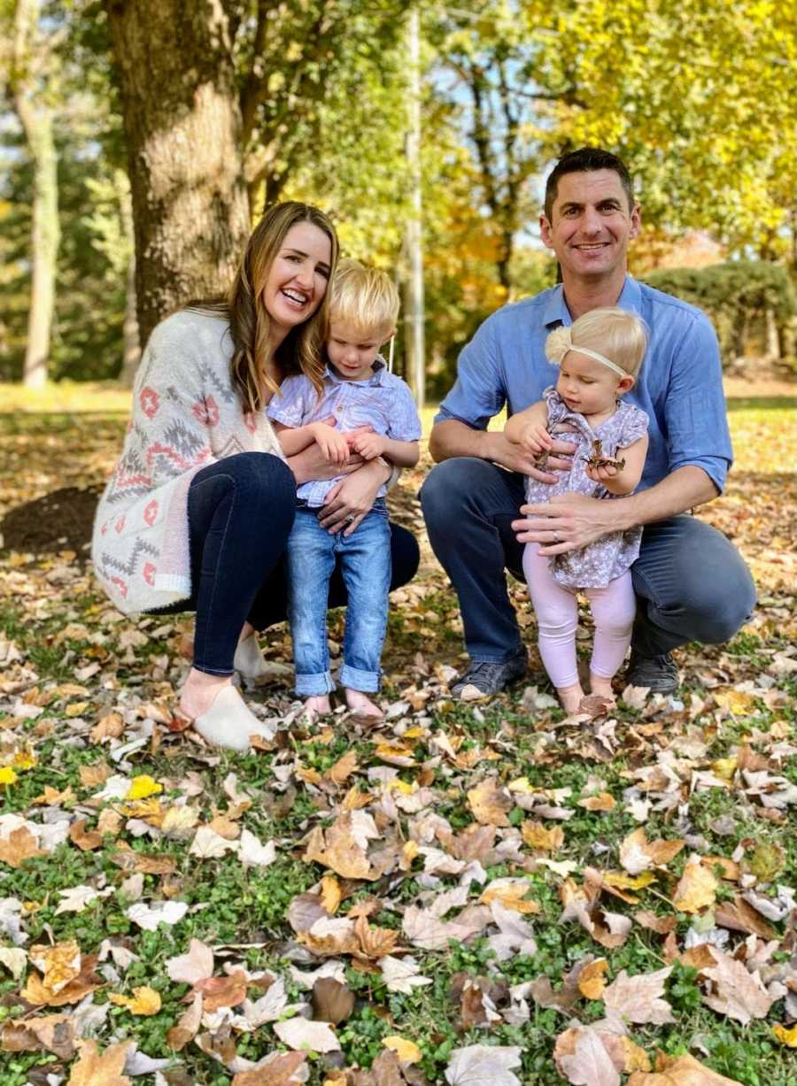 Family of four sitting outside on fall day smiling