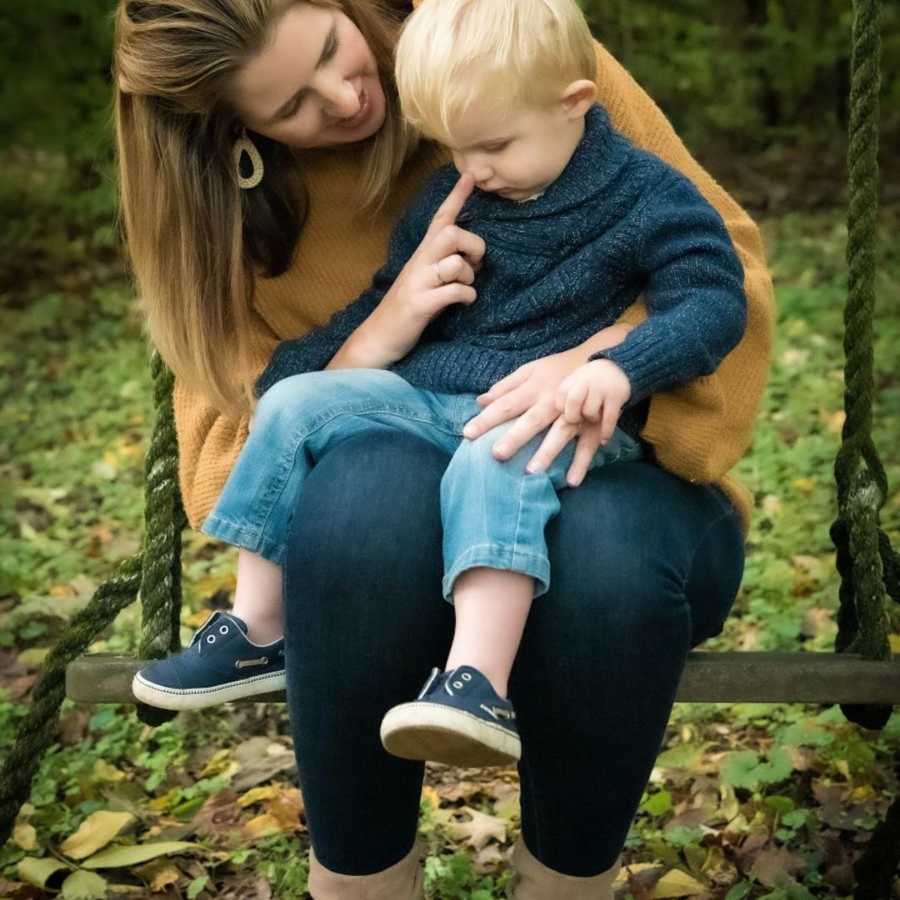 Mom sitting with son outside on lap touching his nose