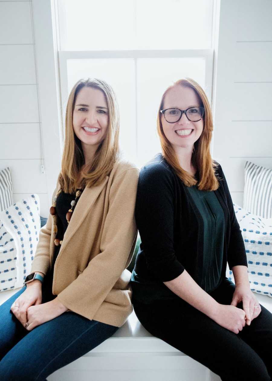 Two women sitting side by side smiling