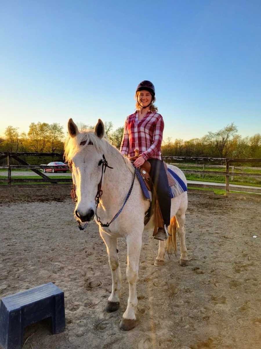 Woman riding a white horse with sunset in the background