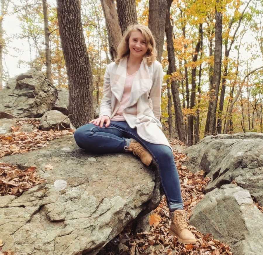 Woman sitting posed on a rock in the woods