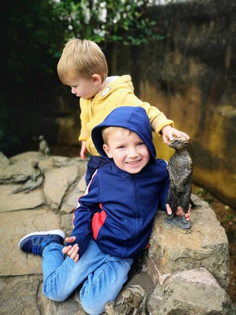 Two brothers playing on rocks wearing raincoats