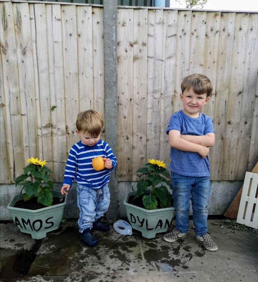 Two brothers wearing blue standing outside by garden