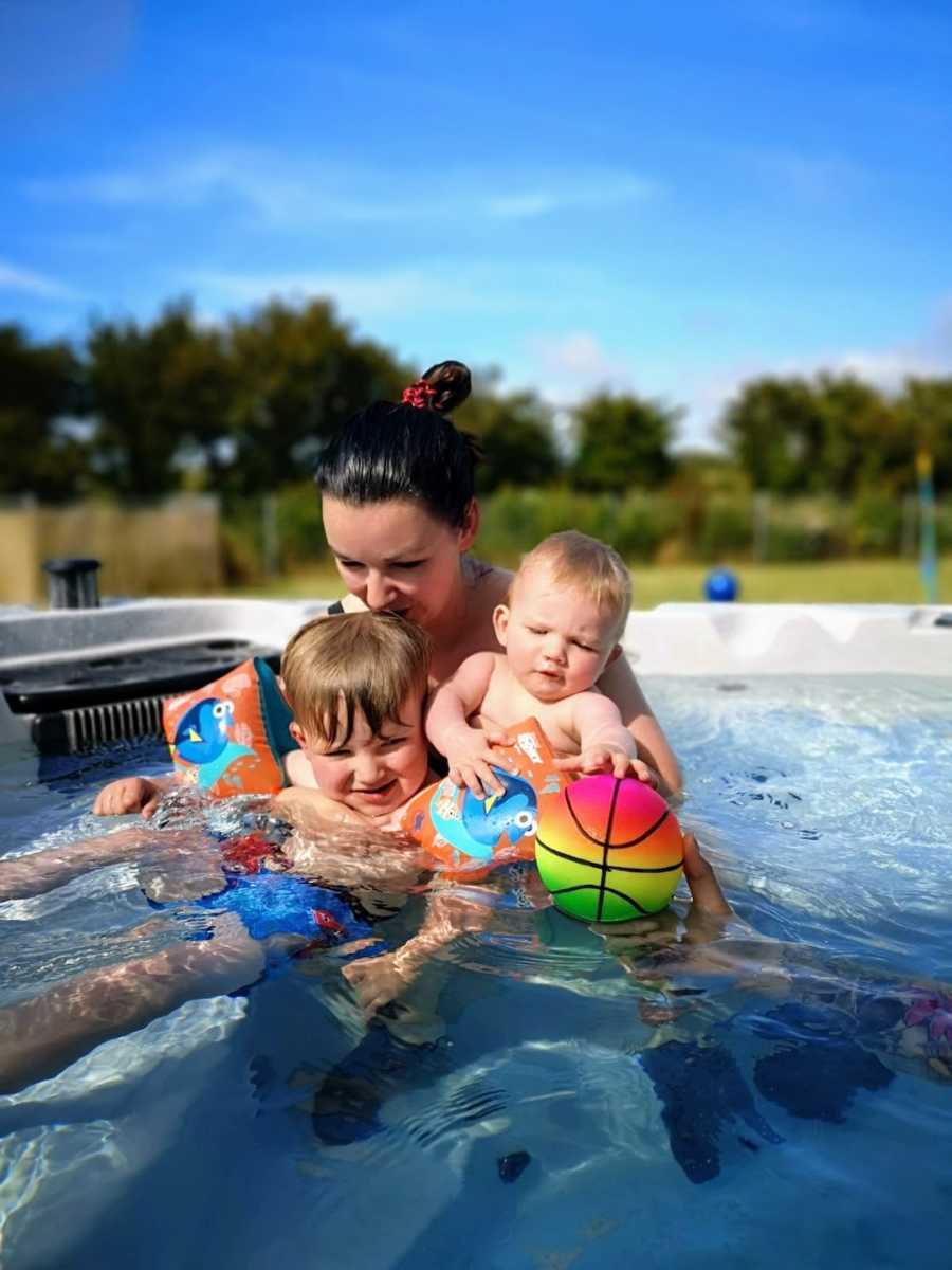 Mom with two sons swimming in pool outside