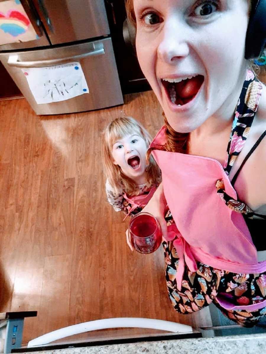 A neurodivergent woman and her daughter with mouths open in the kitchen