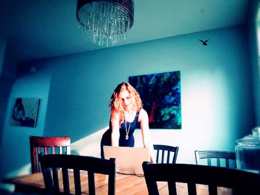 A neurodivergent woman stands working at a computer on a table