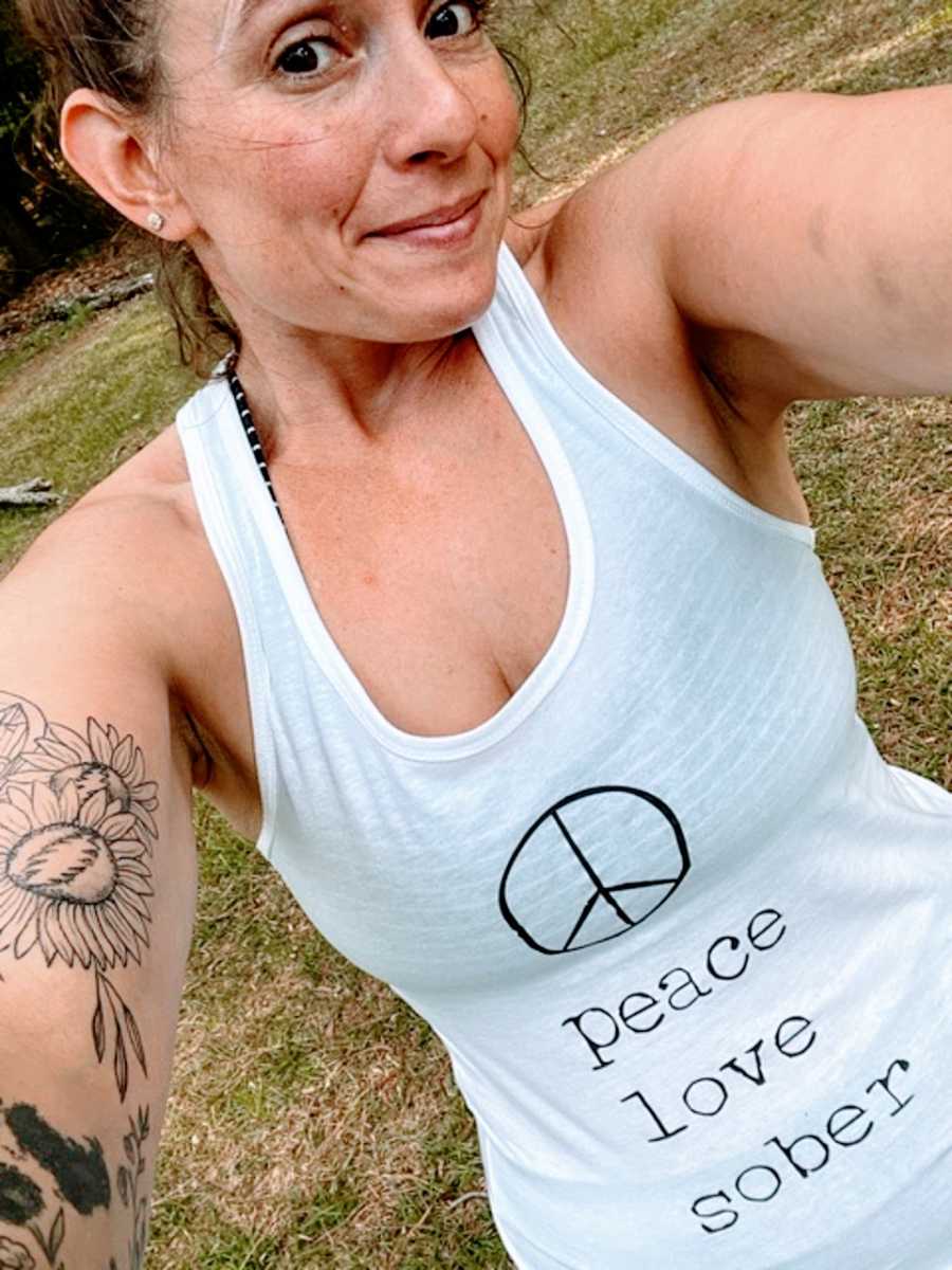 A sober woman wearing a tank top takes a selfie