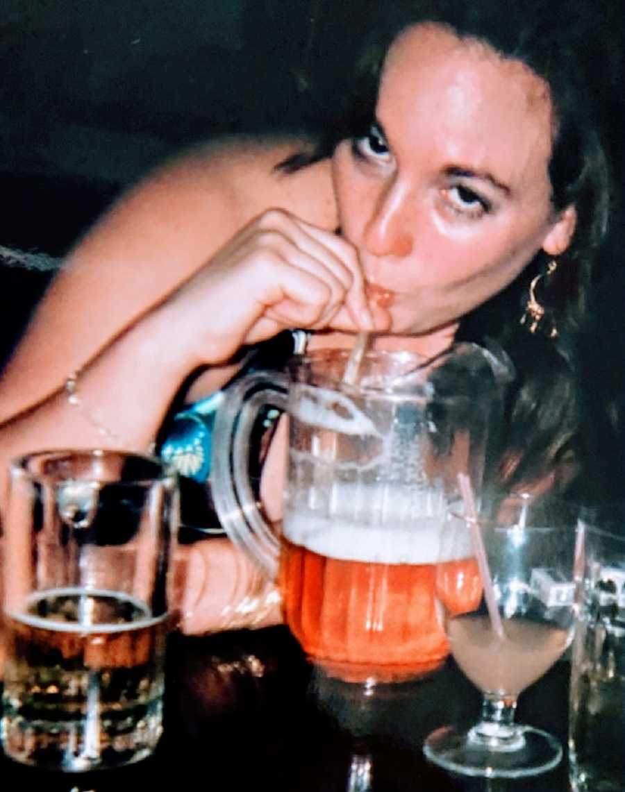 A woman drinks beer from a pitcher using a straw