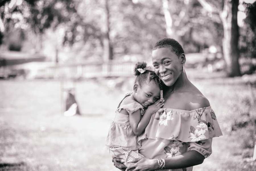 A mother holds her little girl in the park