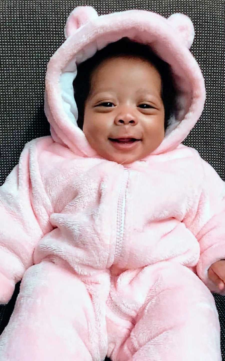 A baby girl wearing a puffy pink onesie