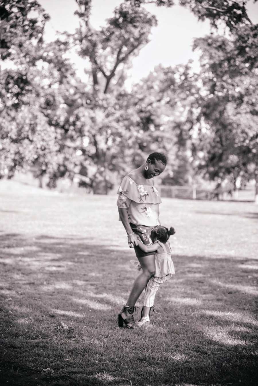 A daughter clings onto her mother's legs in the park