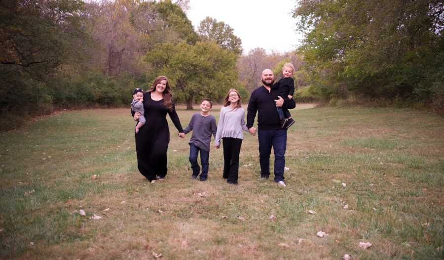 Family of six wearing black walking toward the camera outside