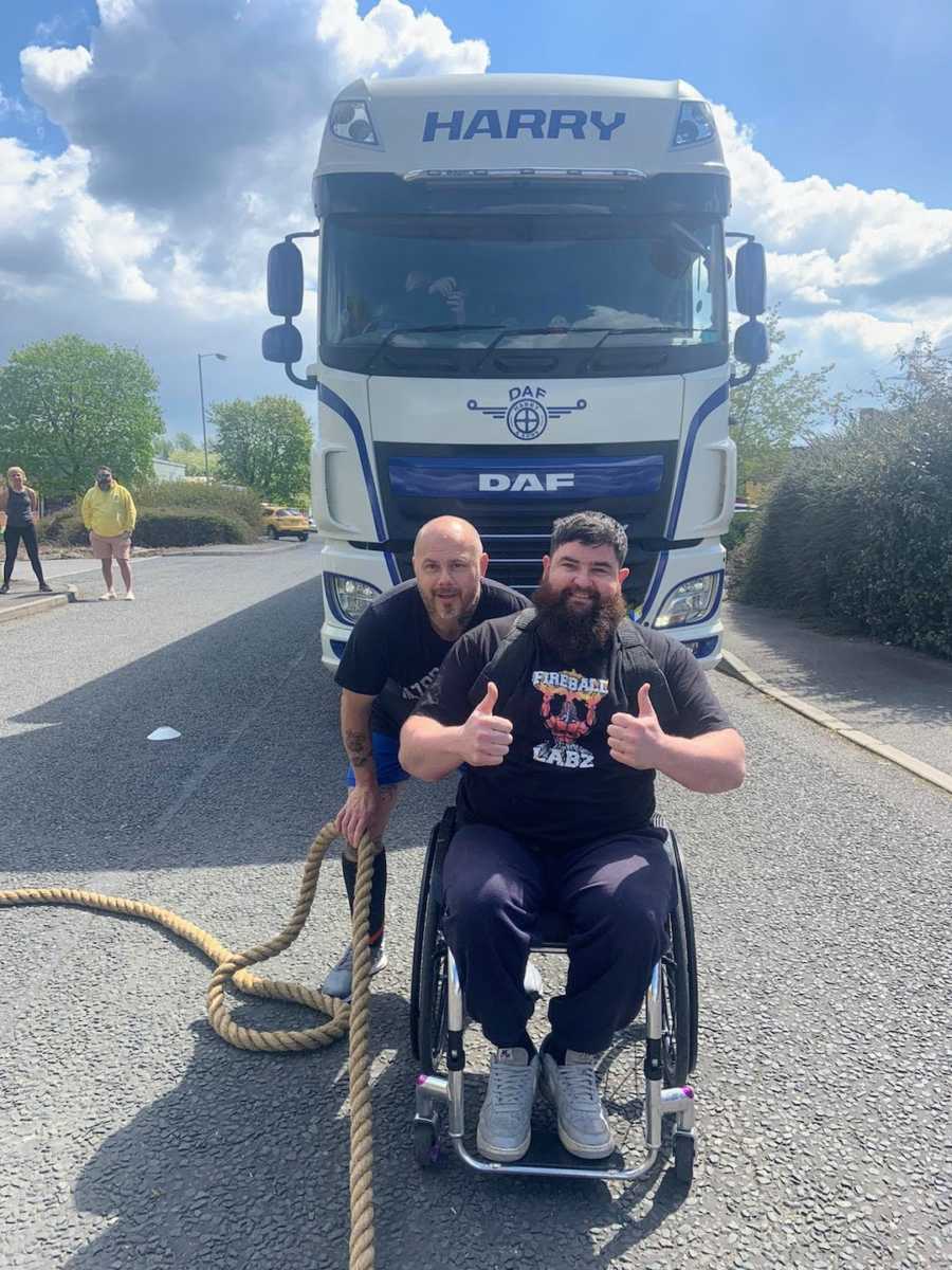 Man in wheelchair doing thumbs-up at weightlifting competition