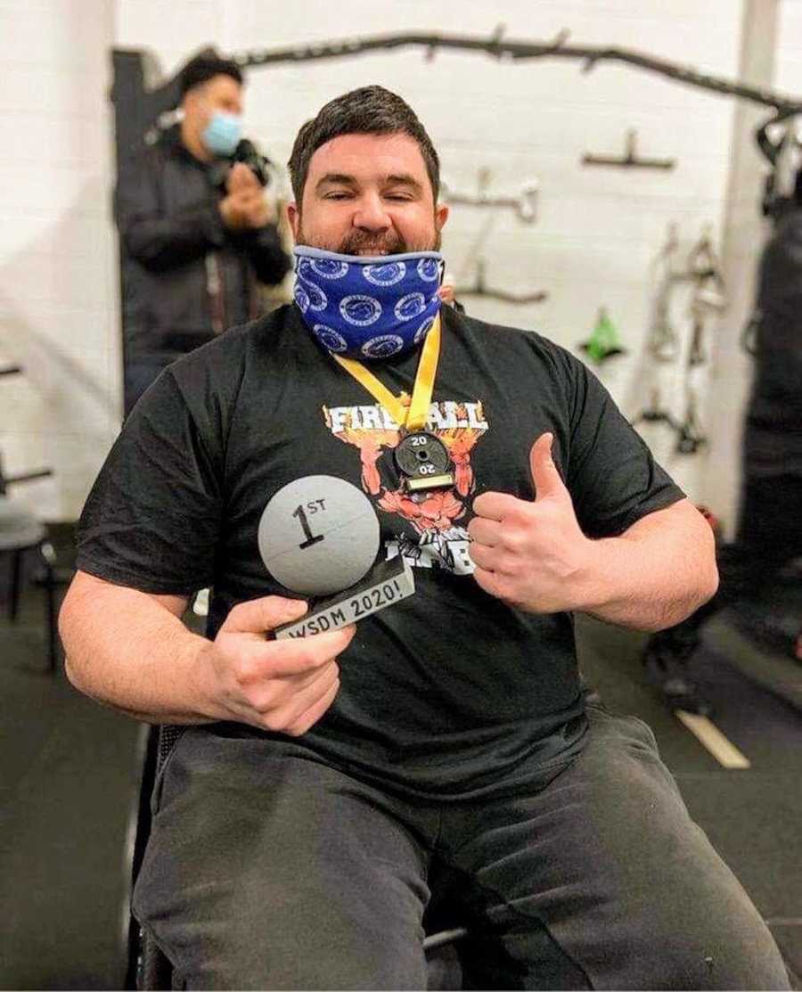Man in wheelchair doing thumbs-up holding medal
