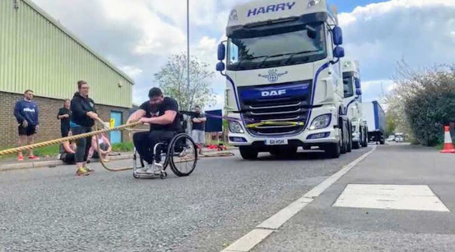 Man in wheelchair pulling bus with rope at Strongman competition