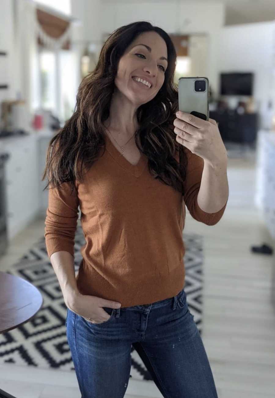 Woman wearing orange shirt taking mirror selfie