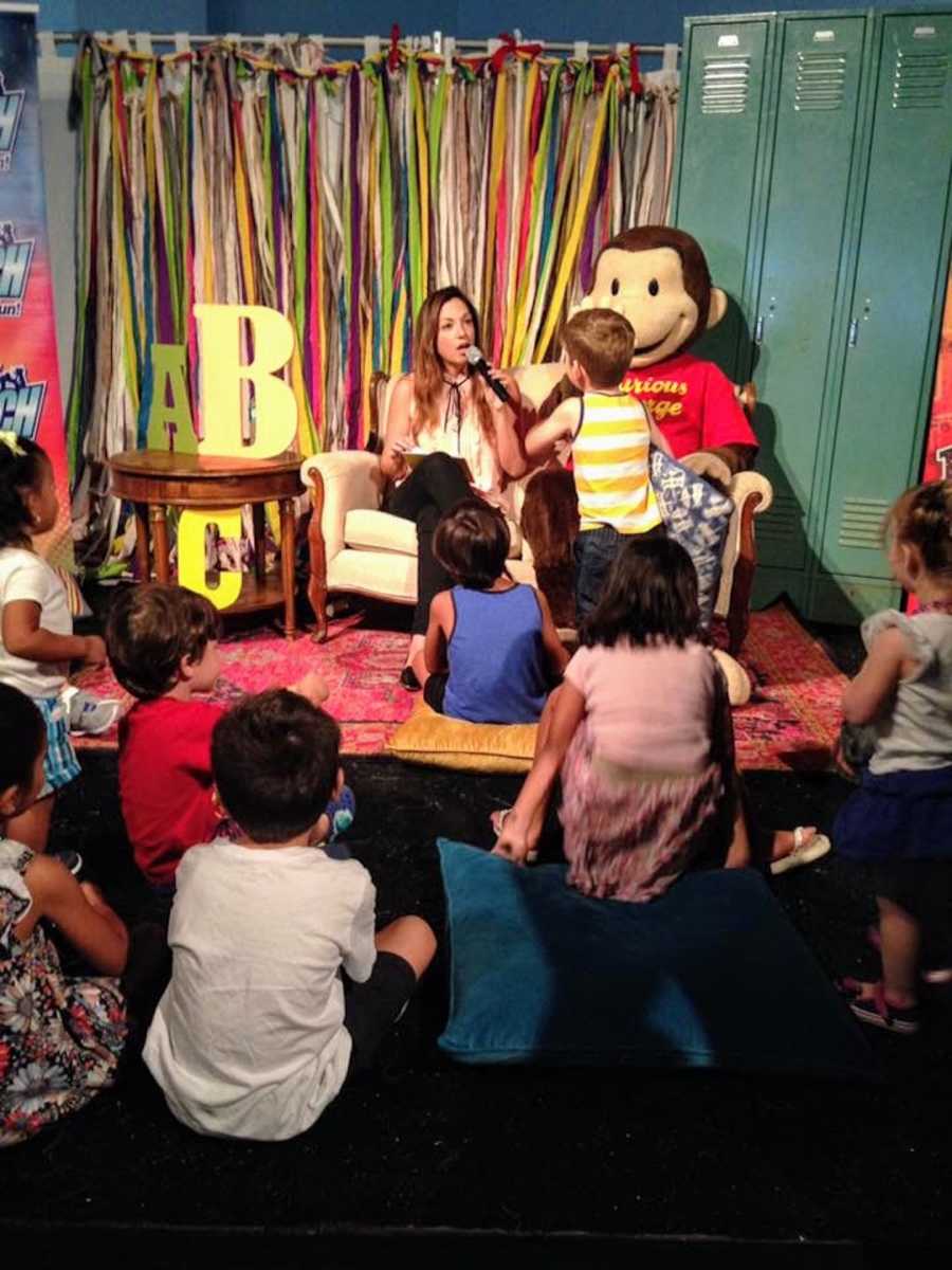 Woman sitting in chair reading to class of children