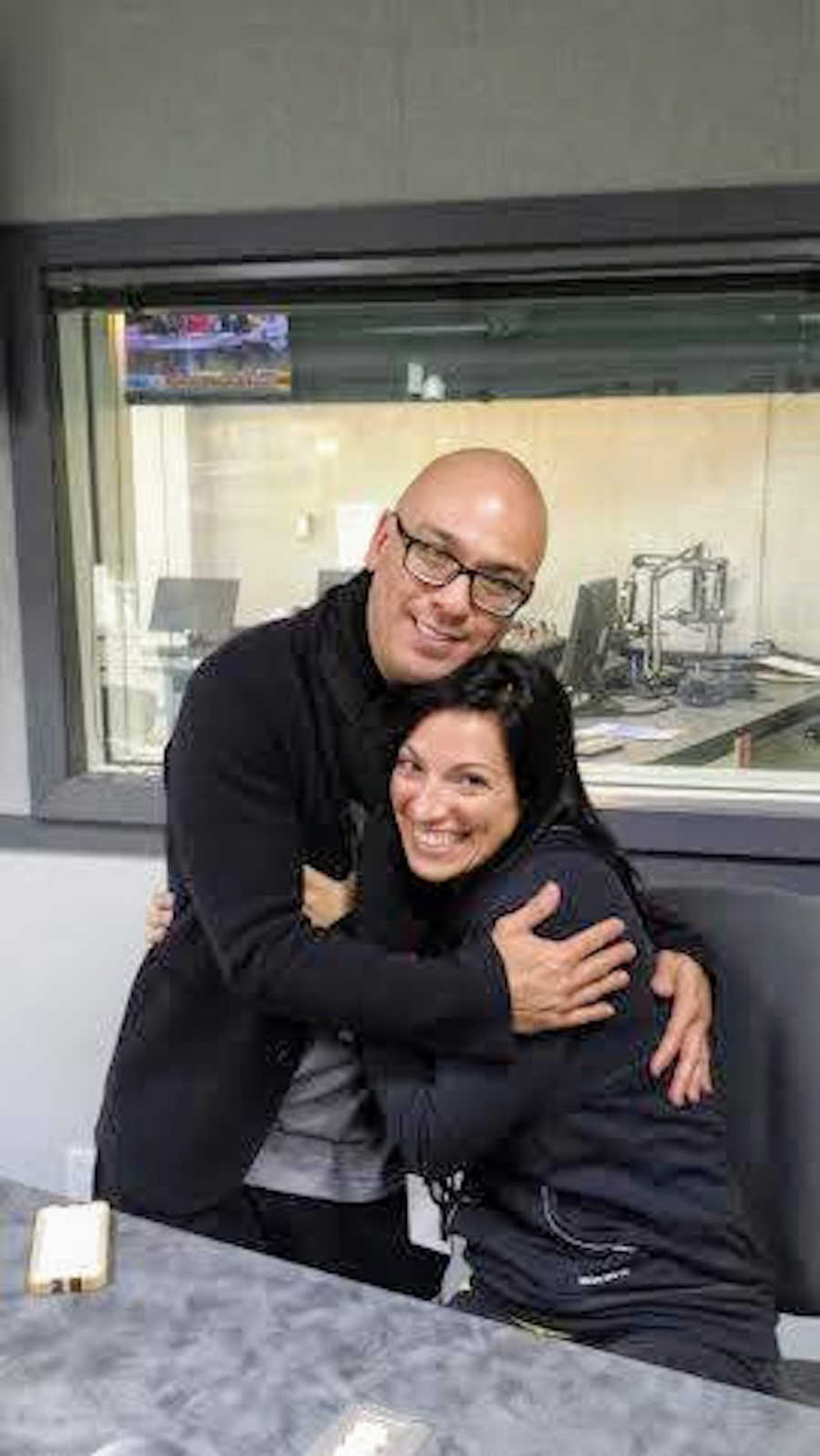 Man hugging woman sitting in chair