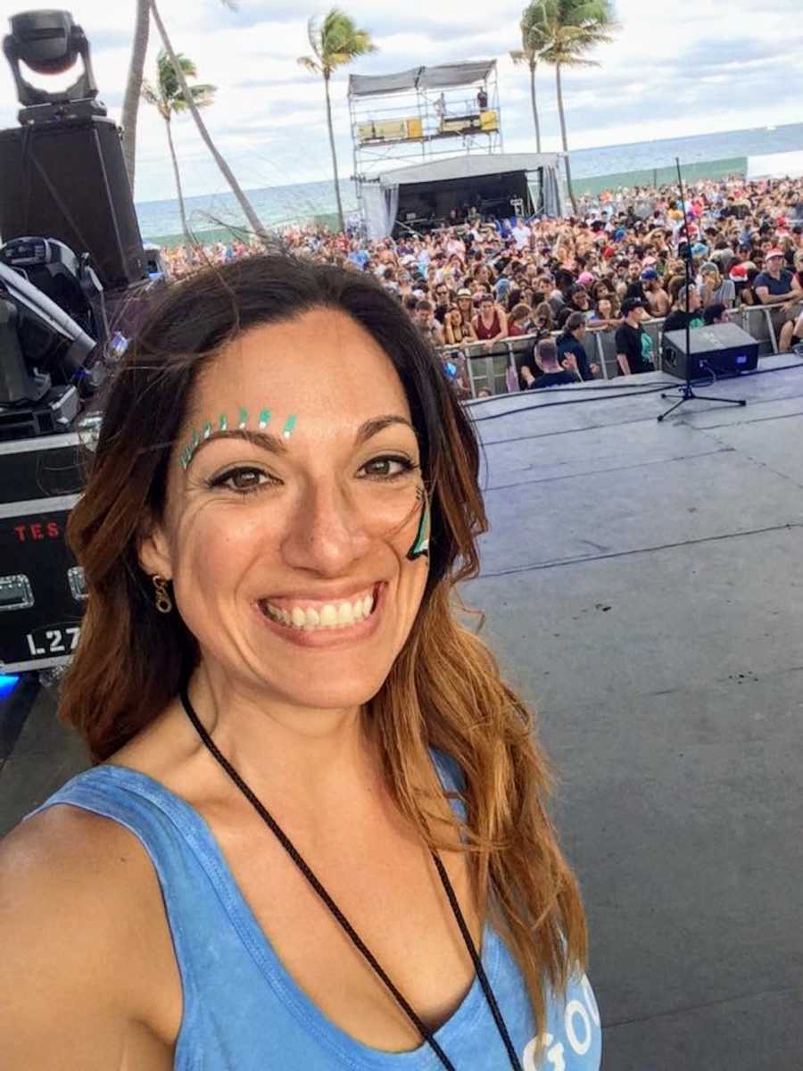 Radio host standing backstage at concert with crowd in the background