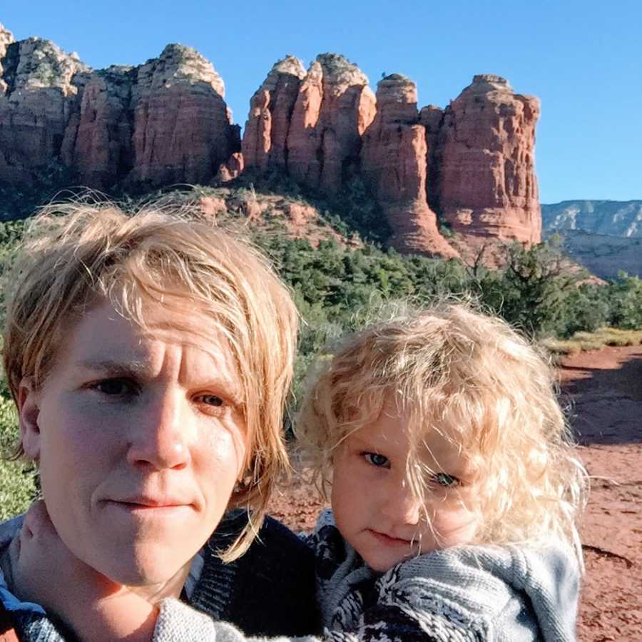 An autistic mother and holds her son in front of a desert landscape