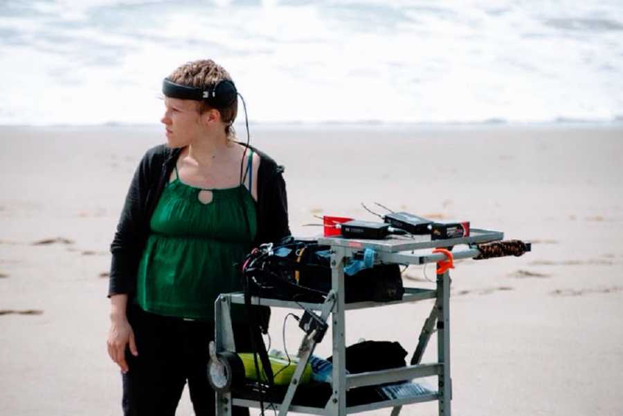 An autistic woman stands next to film sound mixing equipment